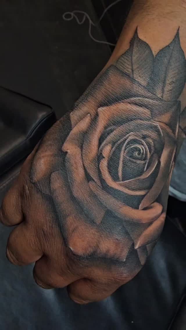 Photorealistic black-and-gray rose tattoo on the hand