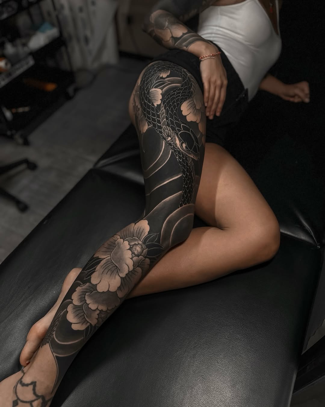 Japanese-inspired blackwork leg sleeve with koi-dragon and peonies