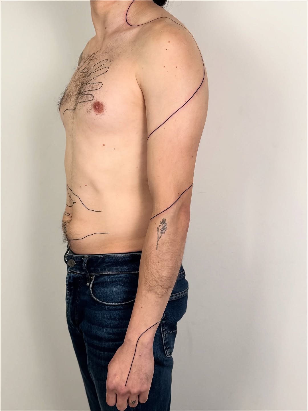 Elegant continuous-line tattoo weaving around shoulder and forearm.