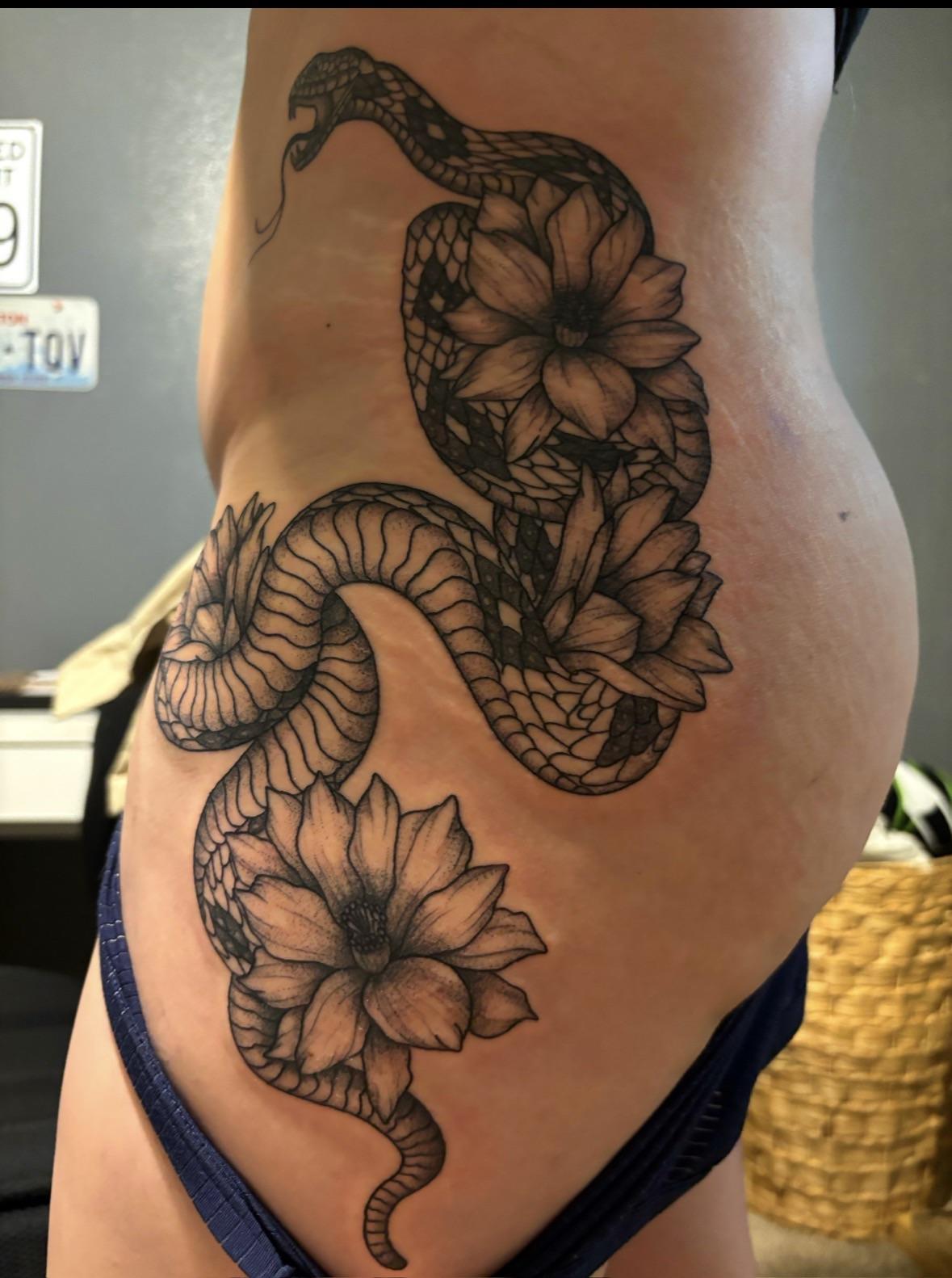 Bold blackwork snake winds around large floral blooms