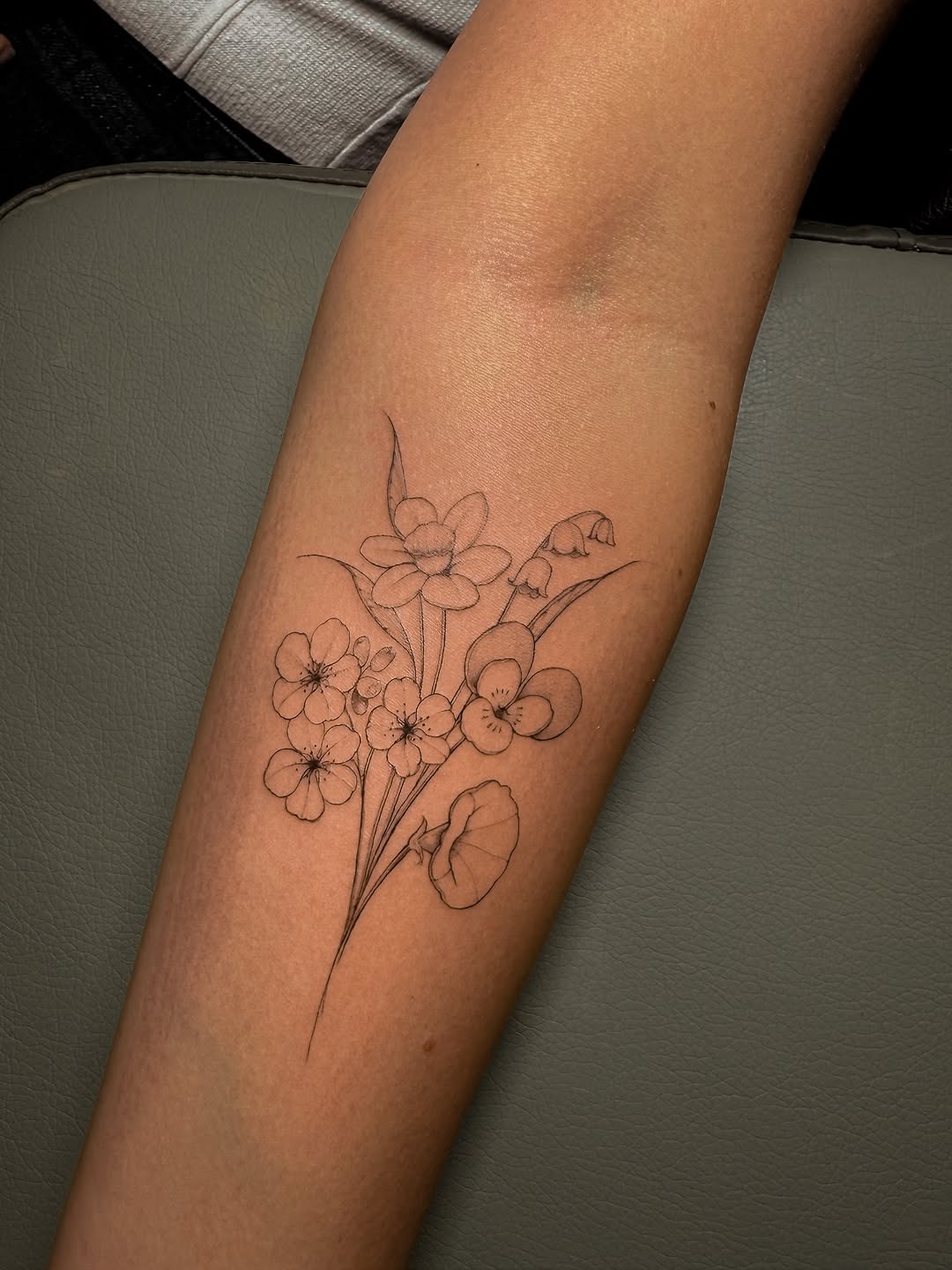 Delicate fine-line bouquet of wildflowers on forearm.