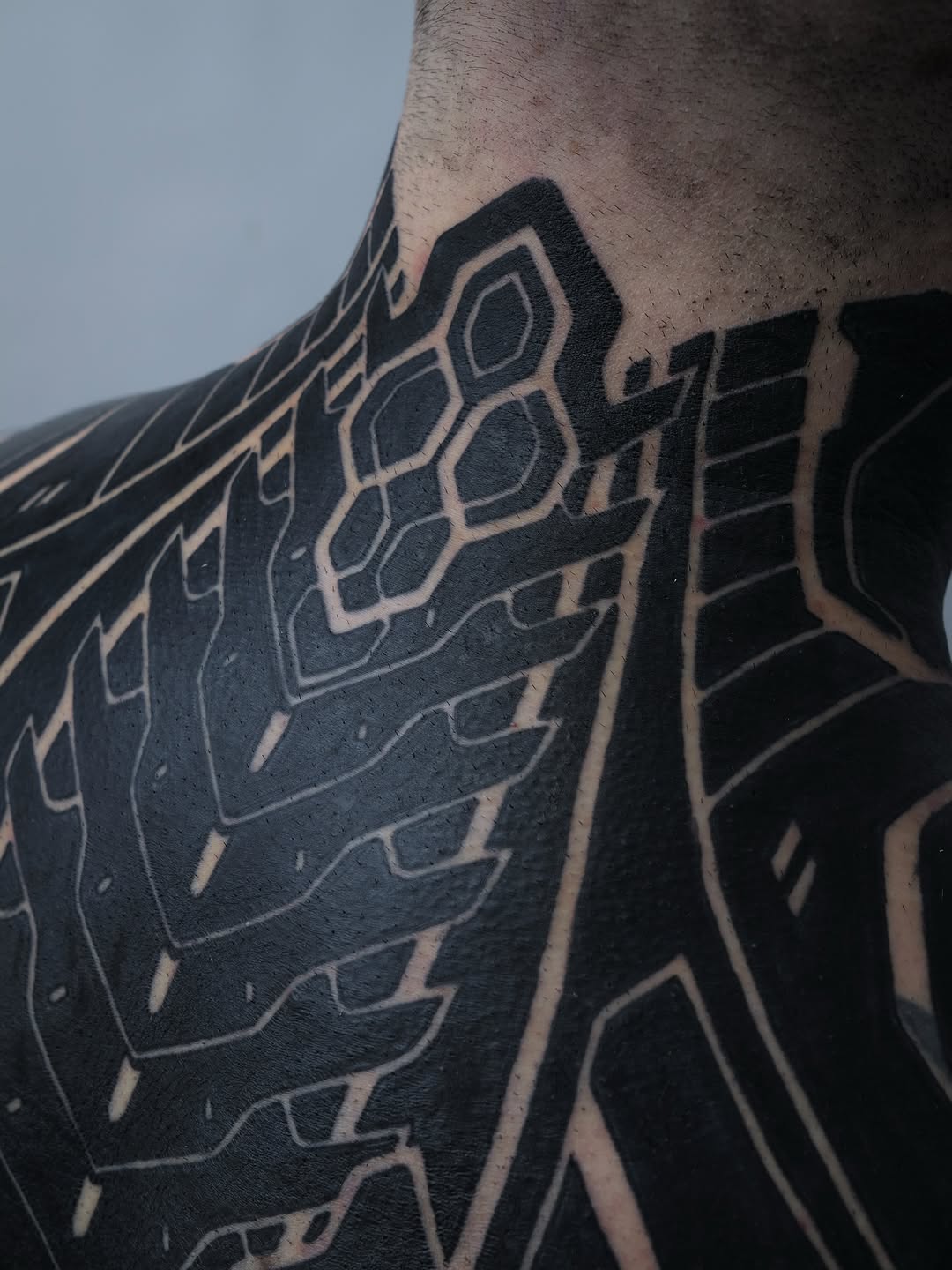 Bold black geometric lattice with hexagonal blocks along shoulder.