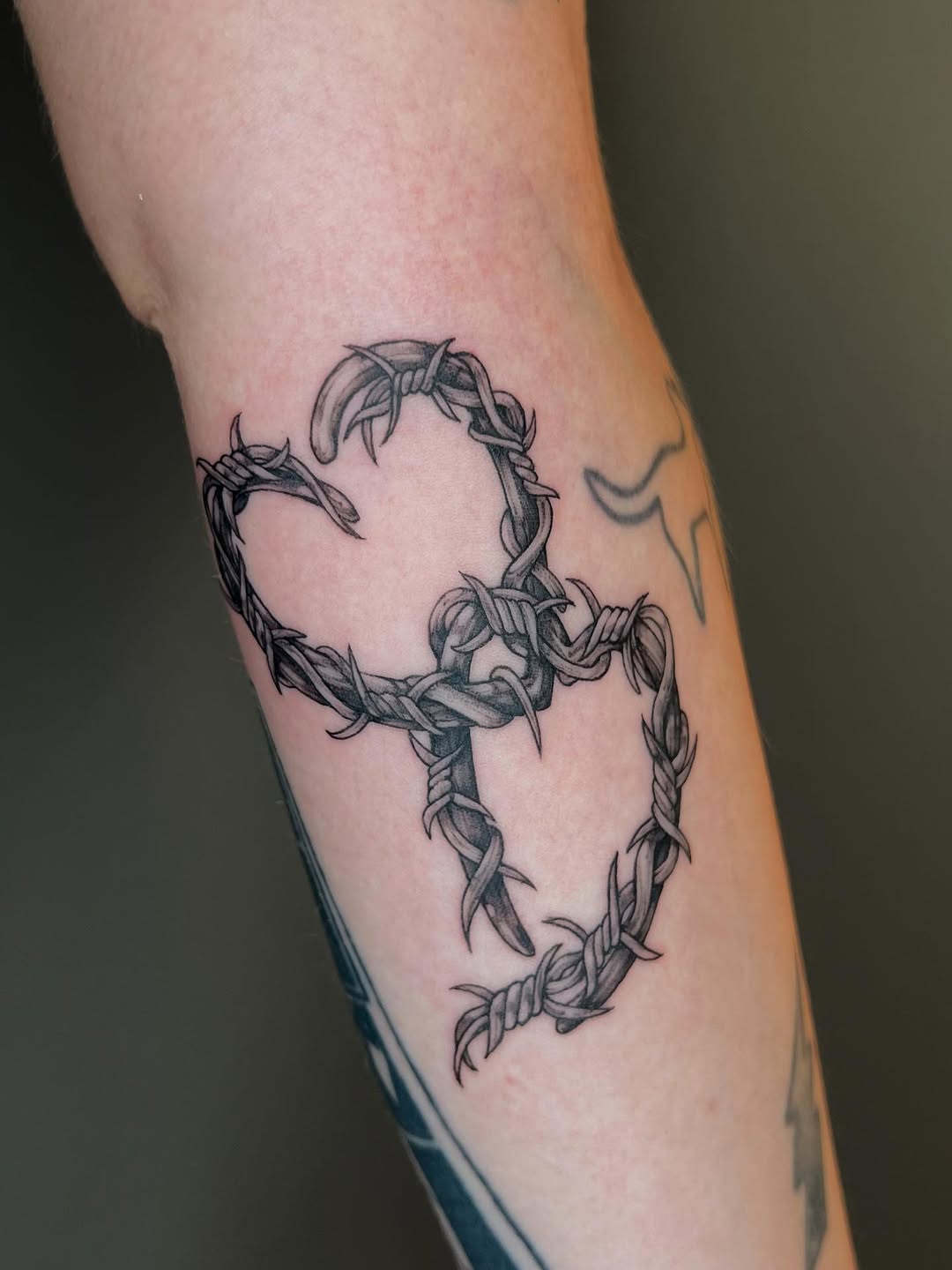 Barbed-wire heart tattoo with bold shading and edge