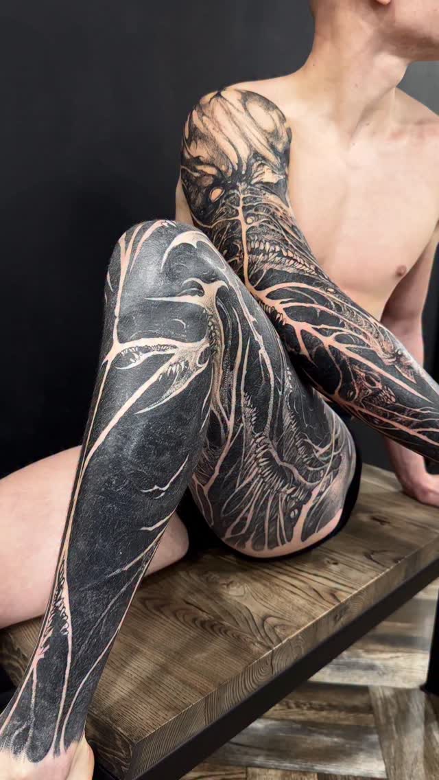 Bold blackwork tattoos wrapping arm and leg with organic motifs