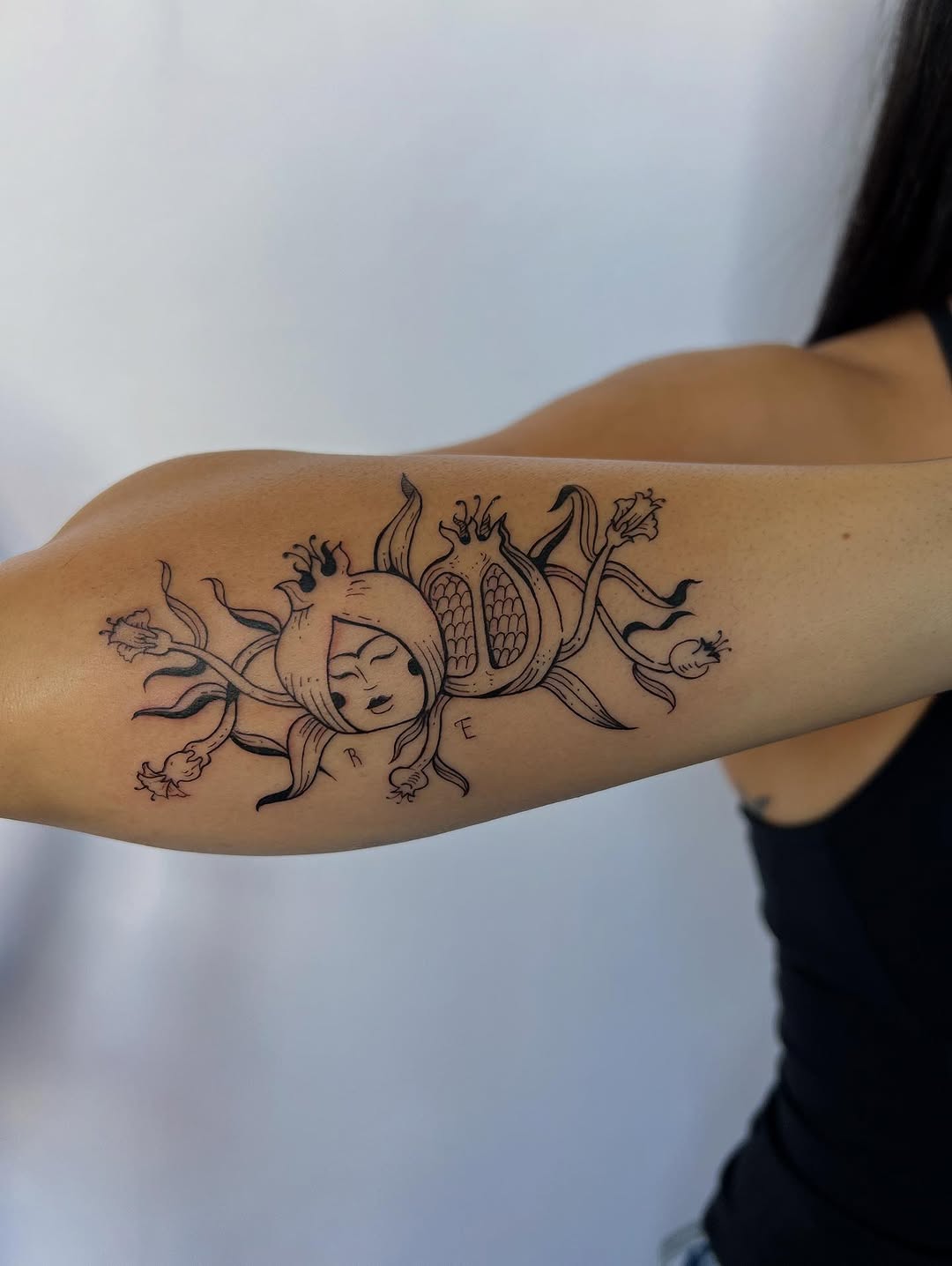 Whimsical sun-face floral tattoo with looping petals