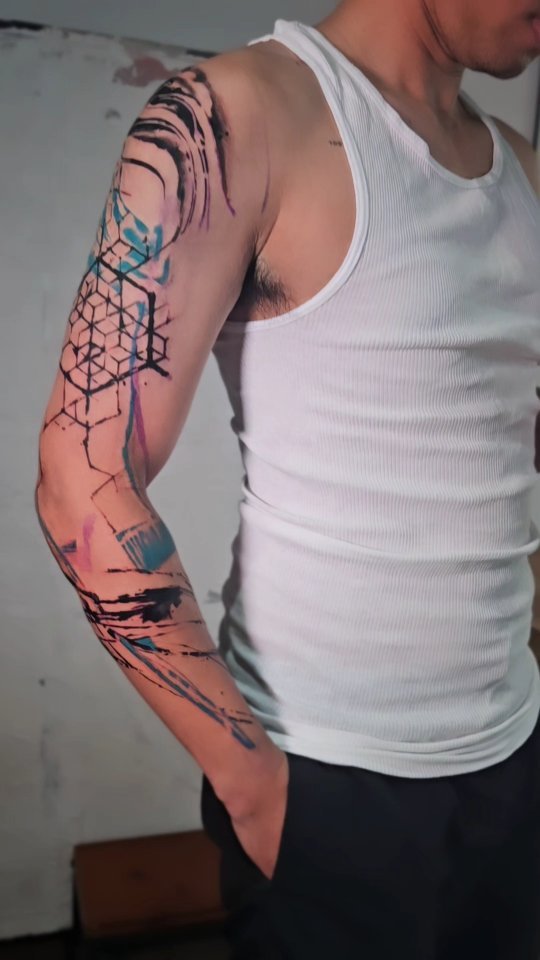 Geometric blackwork with watercolor splashes on forearm.