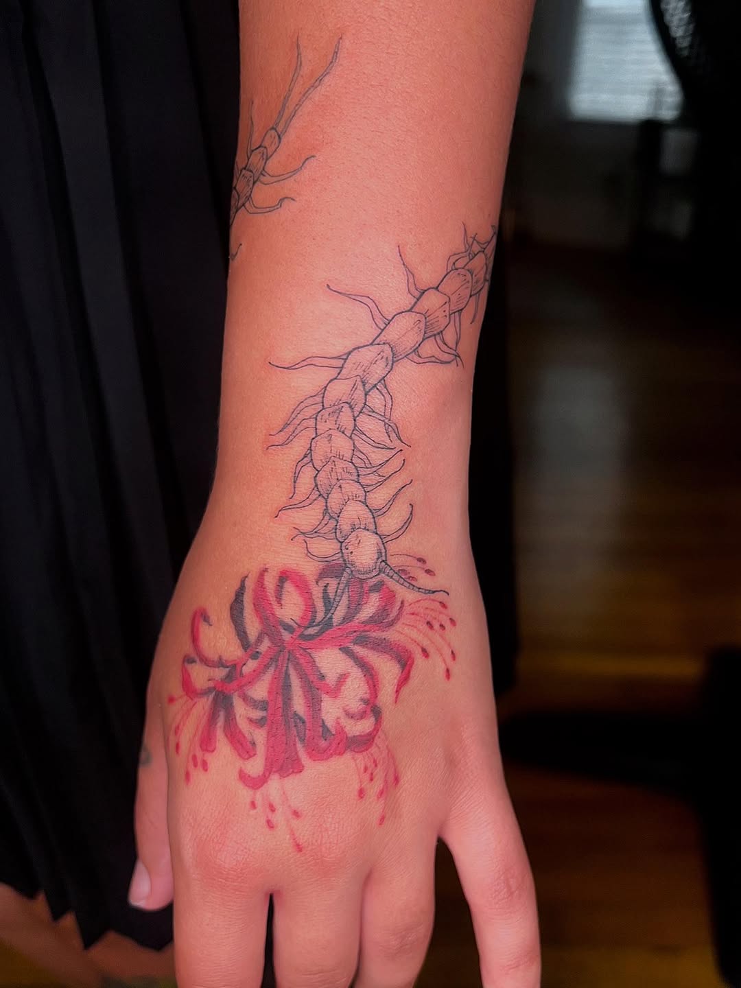 Intricate chained segmentation along forearm ending in red bloom