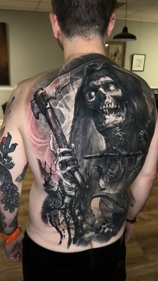 Monumental black-and-gray Grim Reaper backpiece with skulls.
