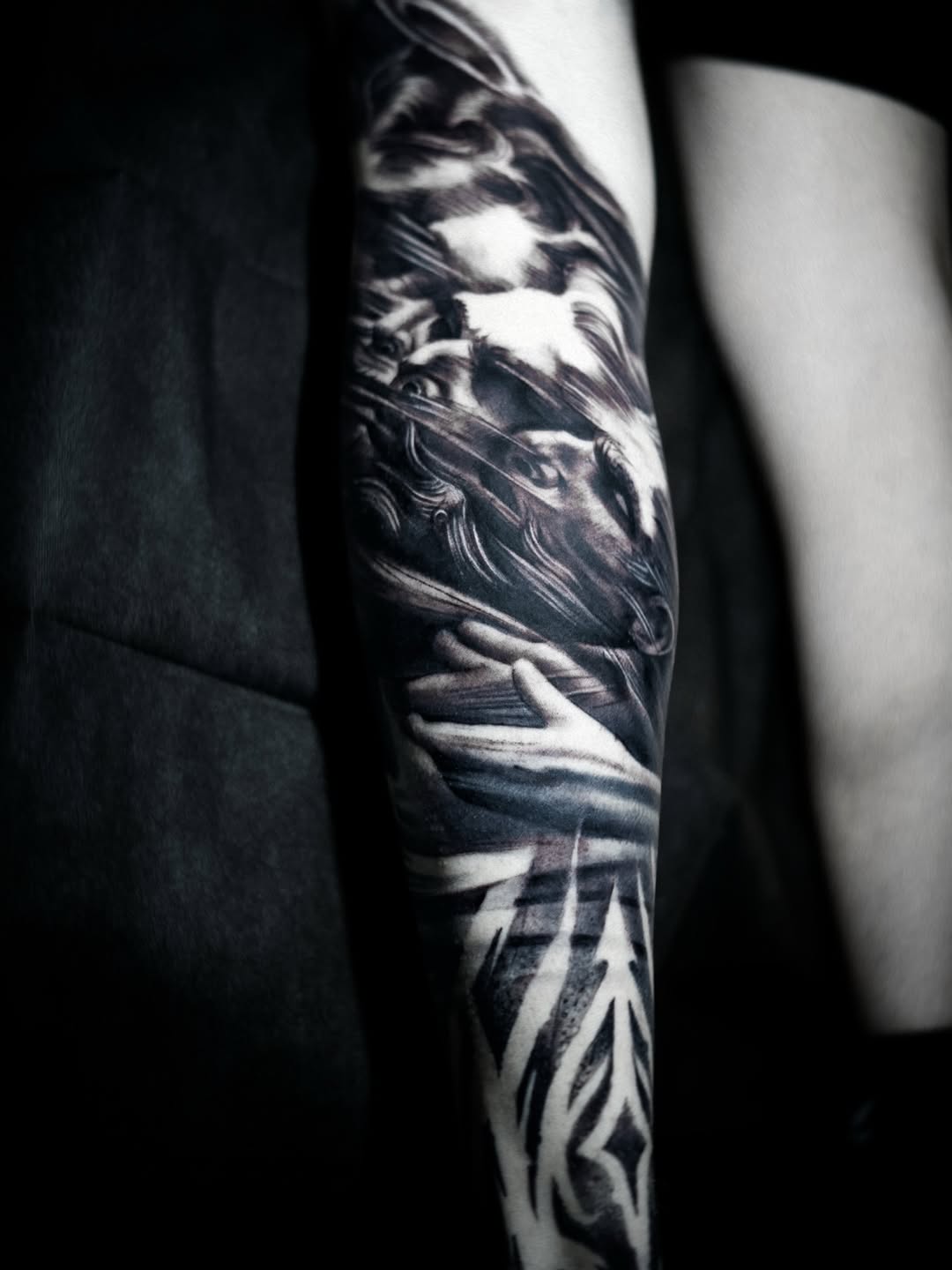 Dramatic black-and-gray forearm sleeve with swirling, dragon-like forms