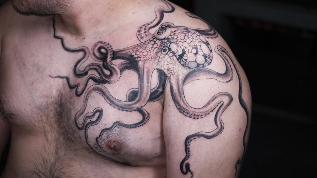 Bold black octopus wraps shoulder with curling tentacles.