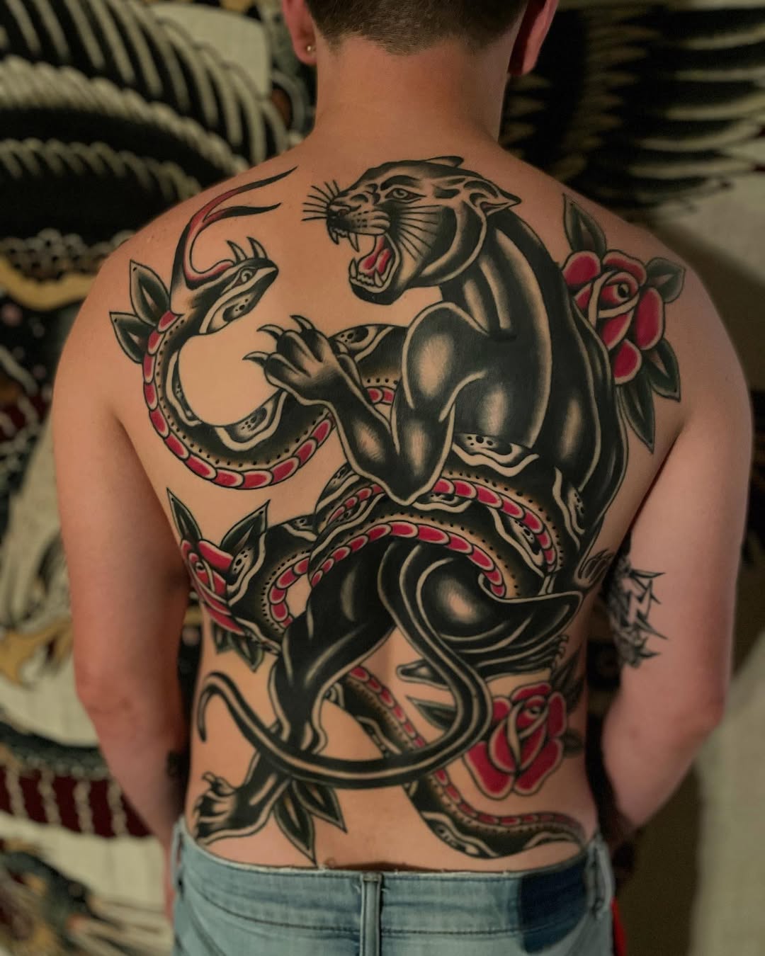Bold traditional back piece: roaring panther, coiled serpent, roses.