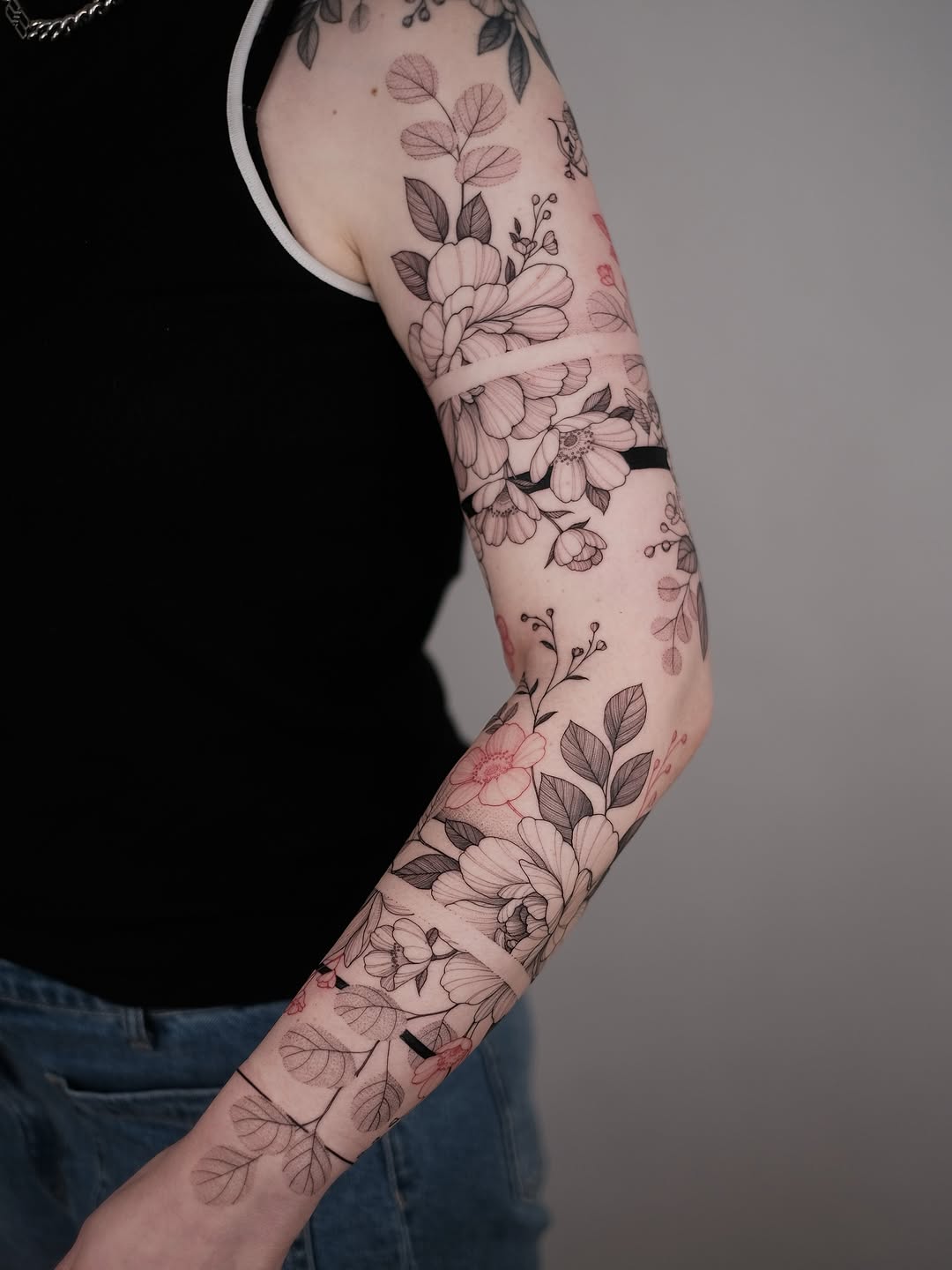 Fine-line botanical floral sleeve in blackwork on arm