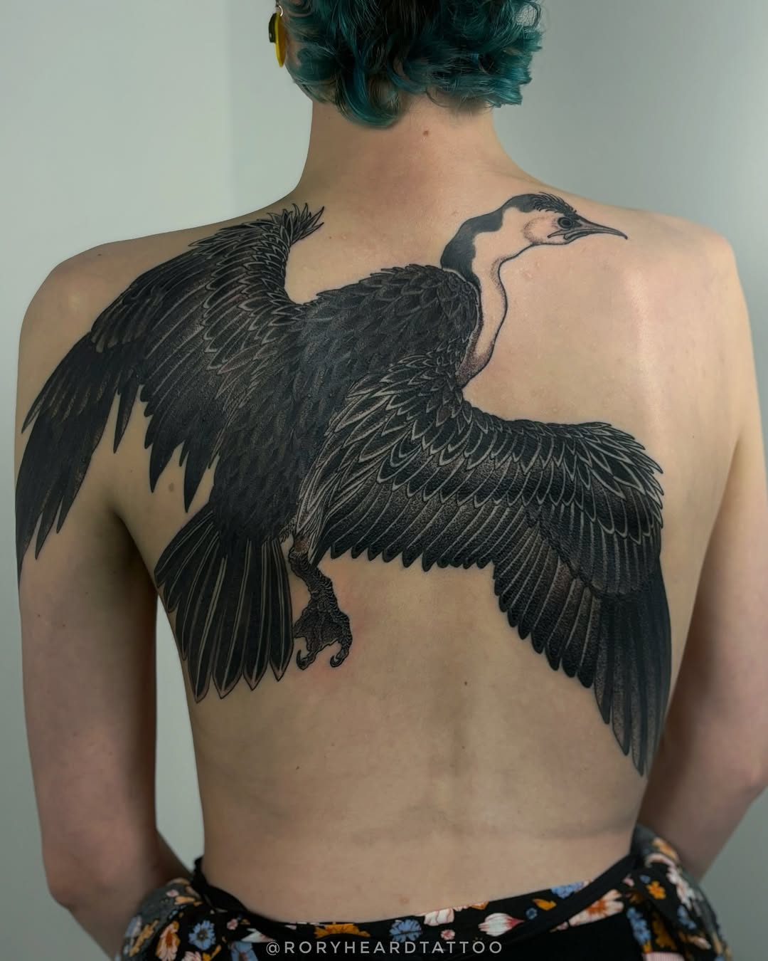 Monumental black crane with intricately feathered wings across back.