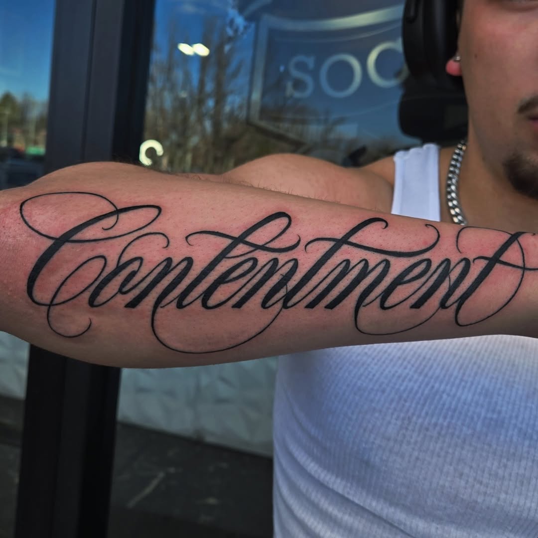 Elegant flowing script reading 'Contentment' on forearm.