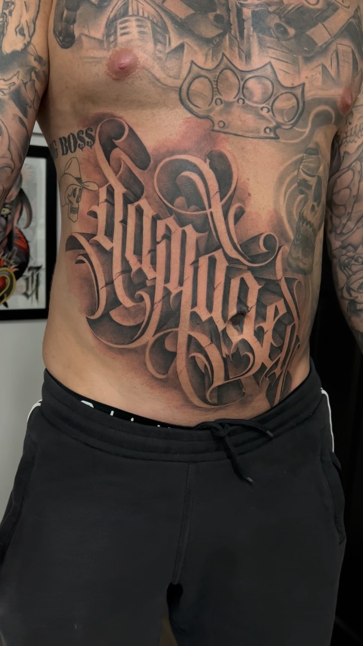 Bold blackletter script chest piece with ornate flourishes