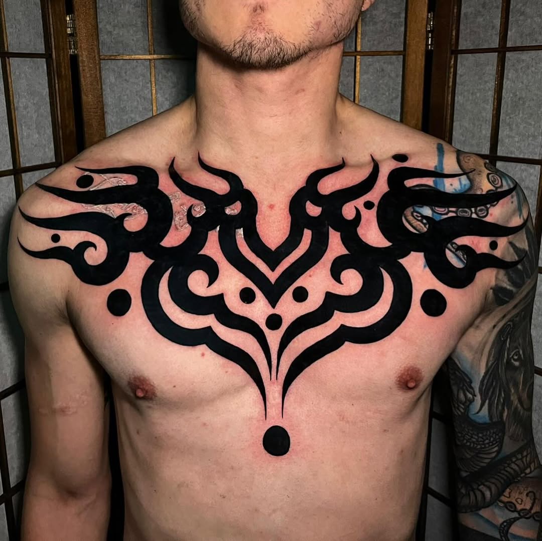Bold symmetrical black tribal chest piece with flame motifs