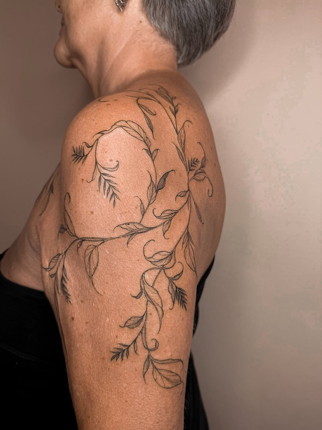 Delicate freehand botanical vines wrap the shoulder.