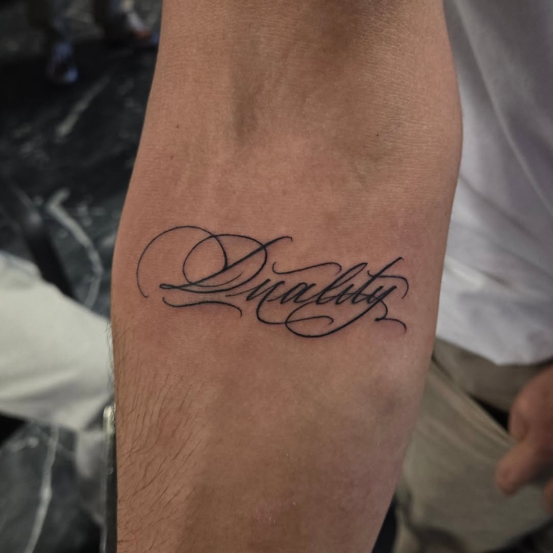 Elegant cursive script reading 'Duality' on inner forearm