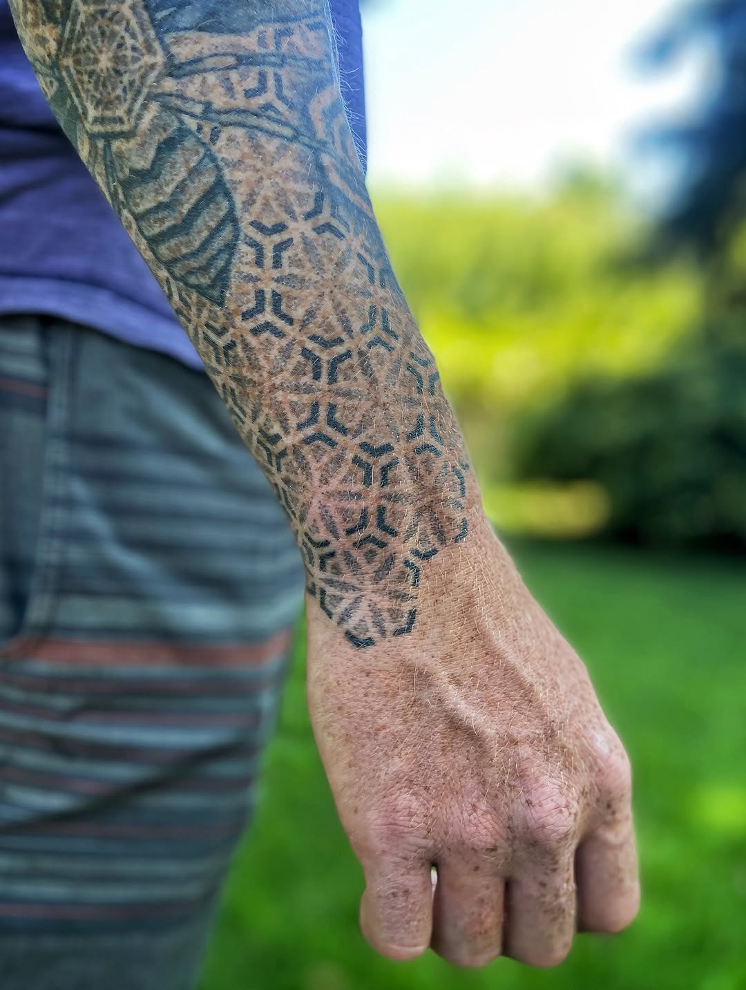 Intricate black geometric tessellation on the forearm.