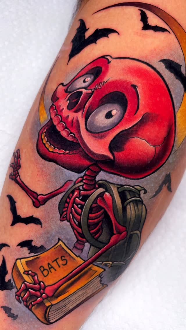 Vibrant neo-traditional skeleton bat tattoo with book motif