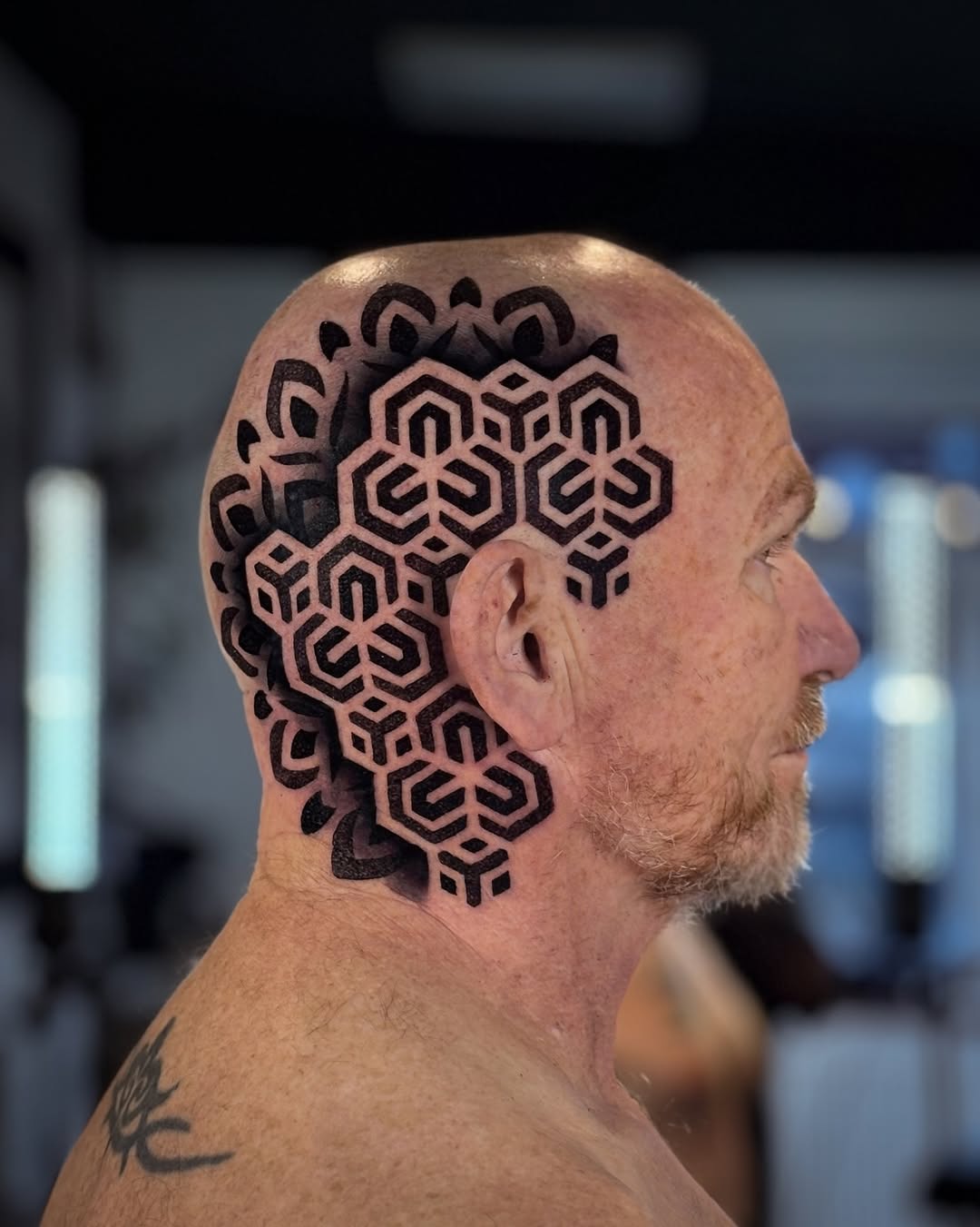 Intricate black geometric motifs cloak bald head and neck