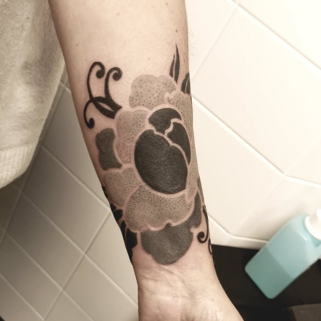 Bold blackwork floral with dotted shading on forearm