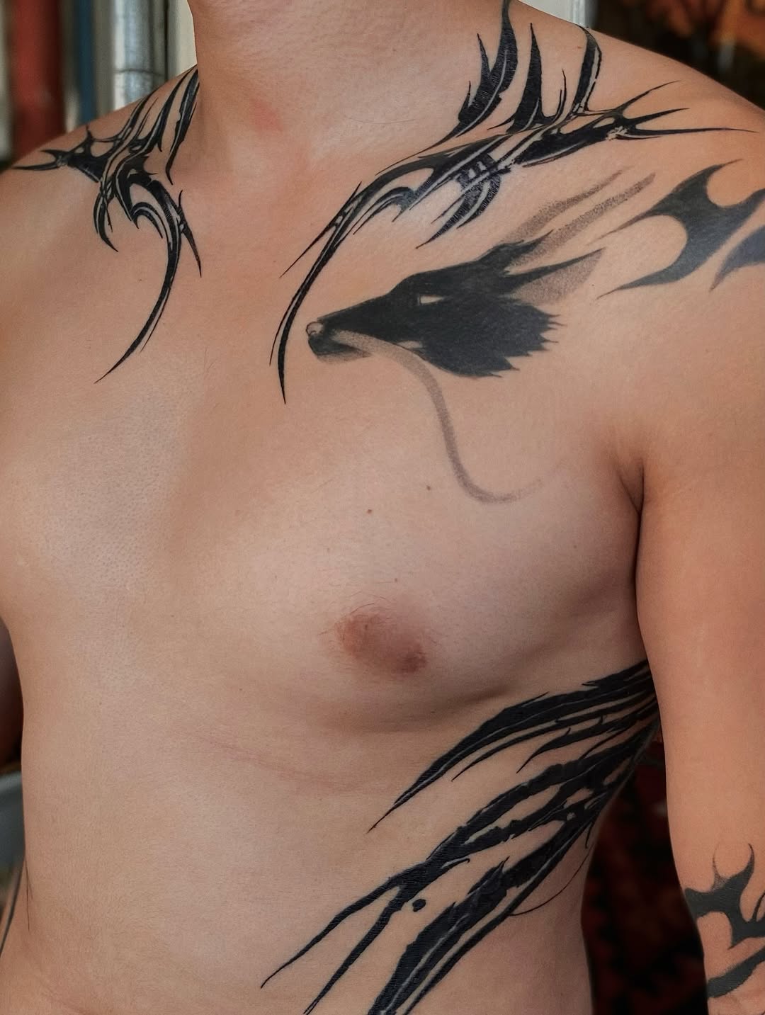 Bold blackwork raven-inspired abstract across shoulder and chest
