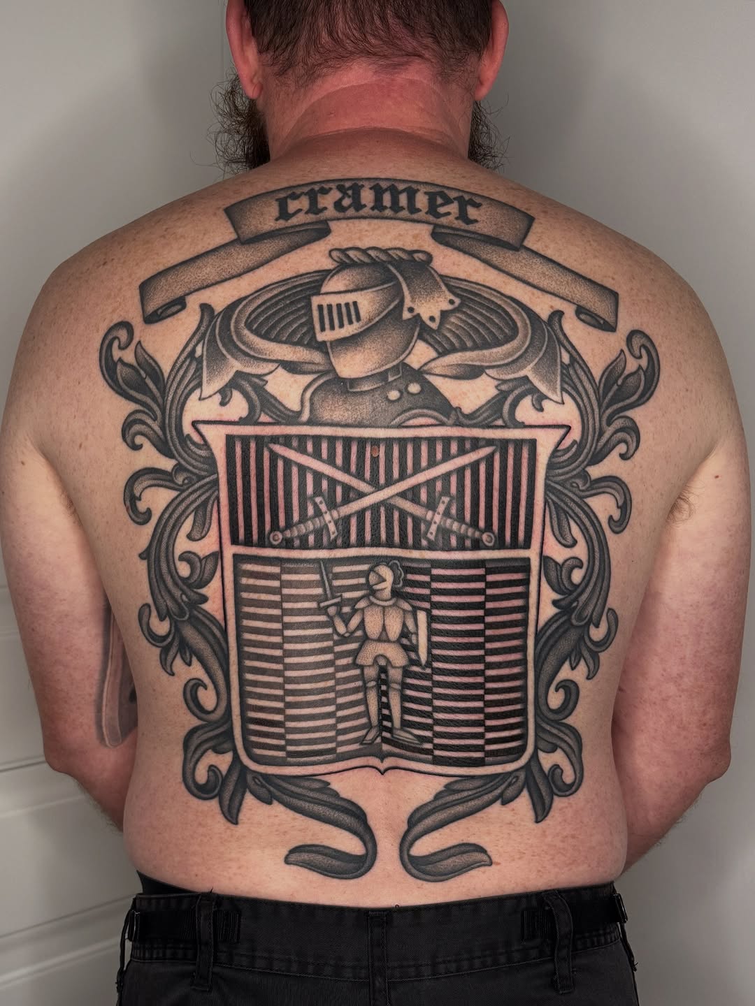 Monumental blackwork backpiece with heraldic shield, knight, and swords.