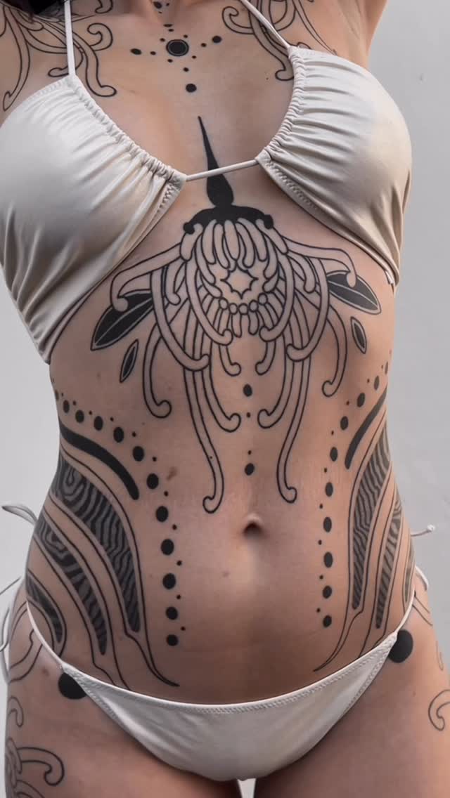Symmetrical blackwork ornament spanning chest to abdomen.