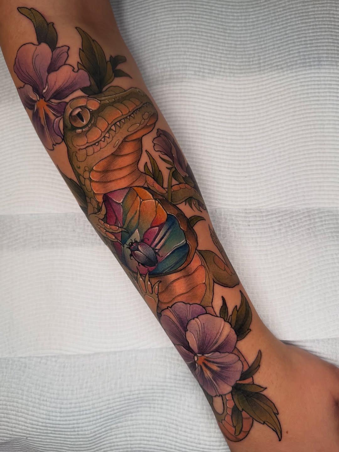 Bold neo-traditional crocodile with vibrant florals and leaves.