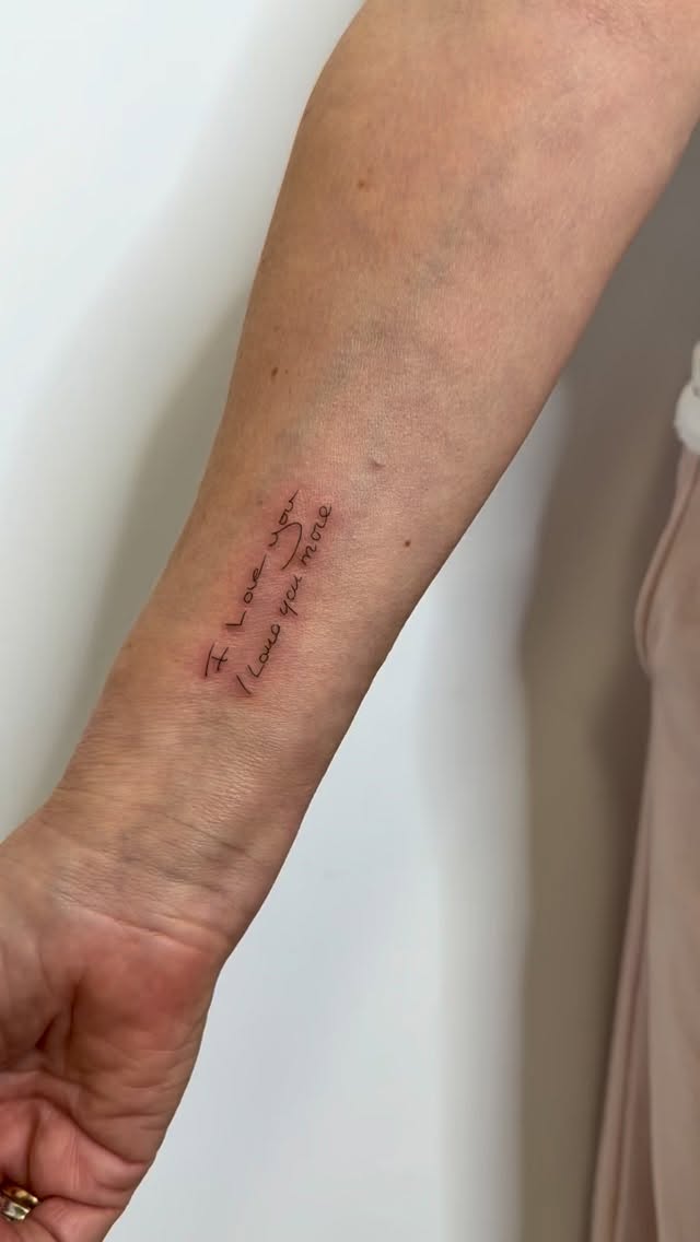 Delicate cursive quote in fine-line script on forearm.