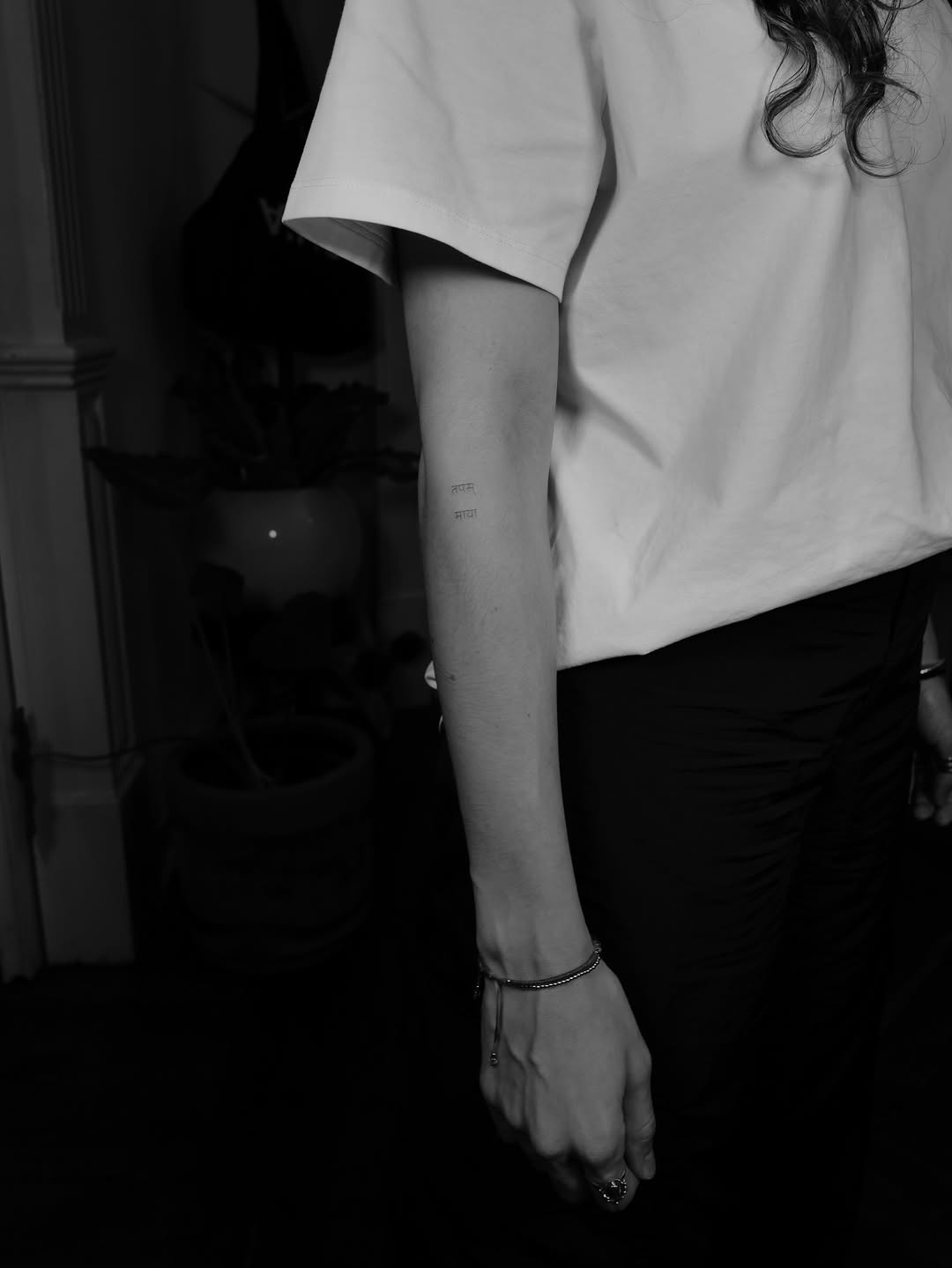 Tiny Devanagari script tattoo on the inner forearm.