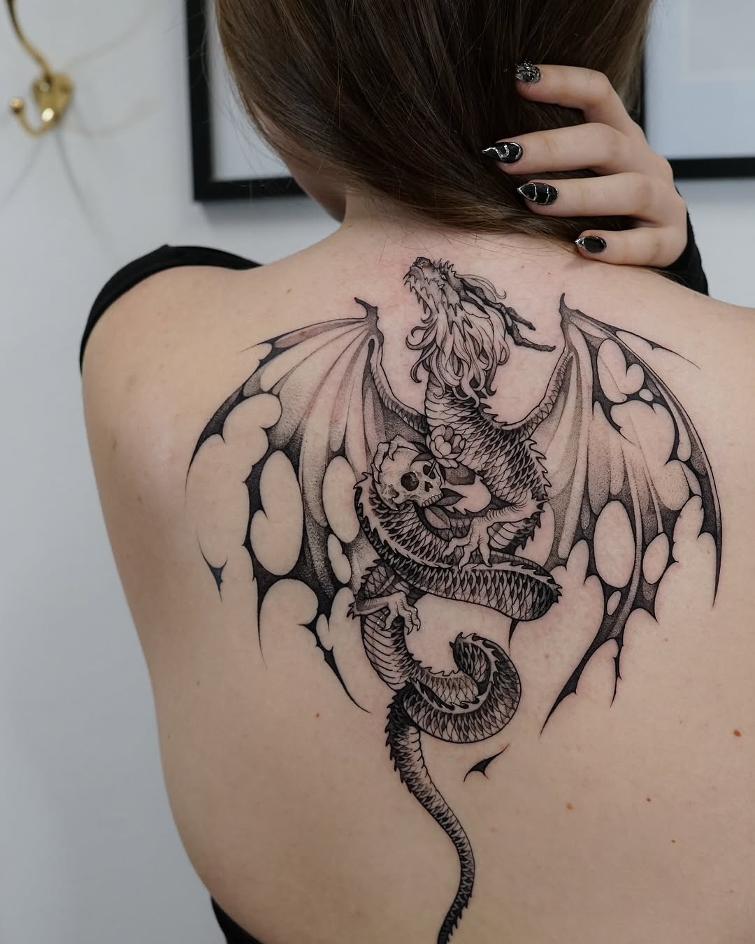 Gothic blackwork dragon with wings and skull.
