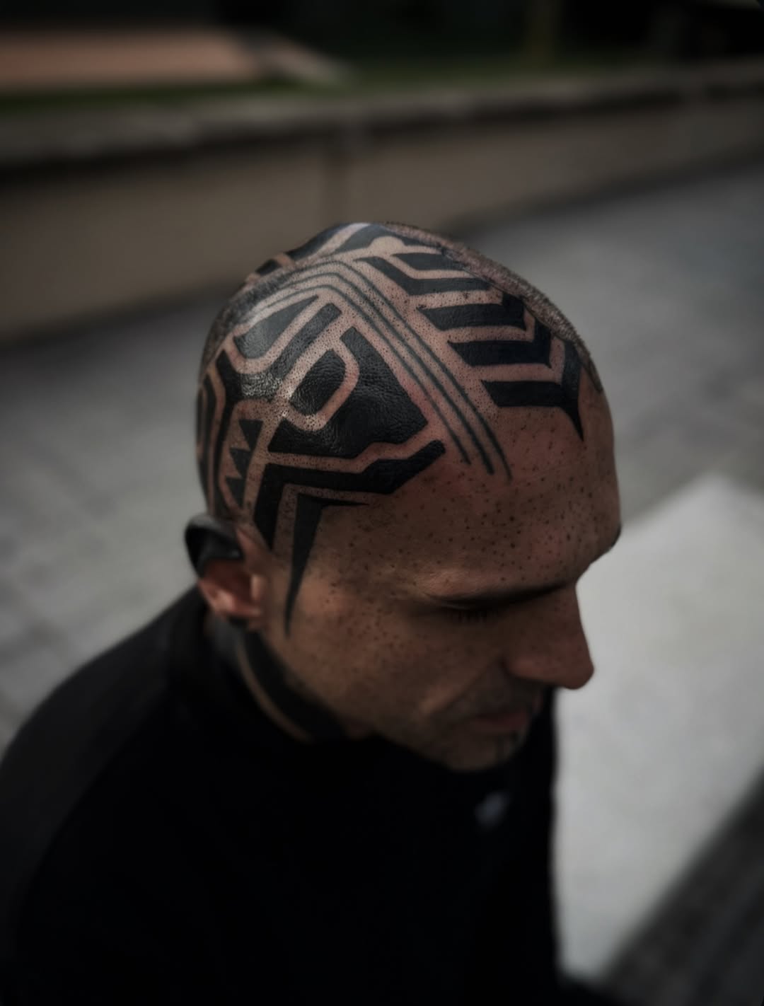 Bold geometric blackwork scalp tattoo with interlocking patterns