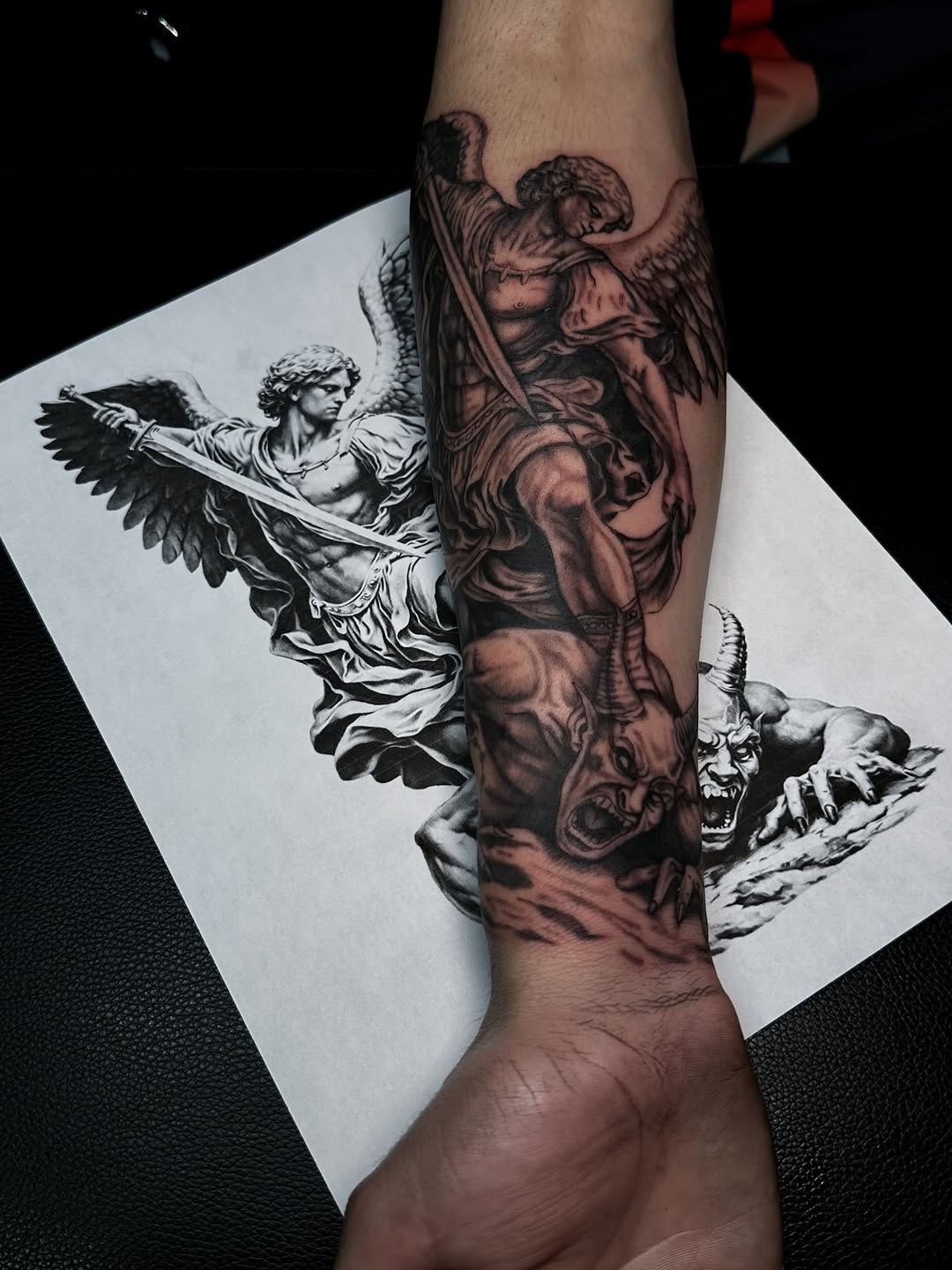 Dramatic black-and-gray archangel with sword, demon underfoot