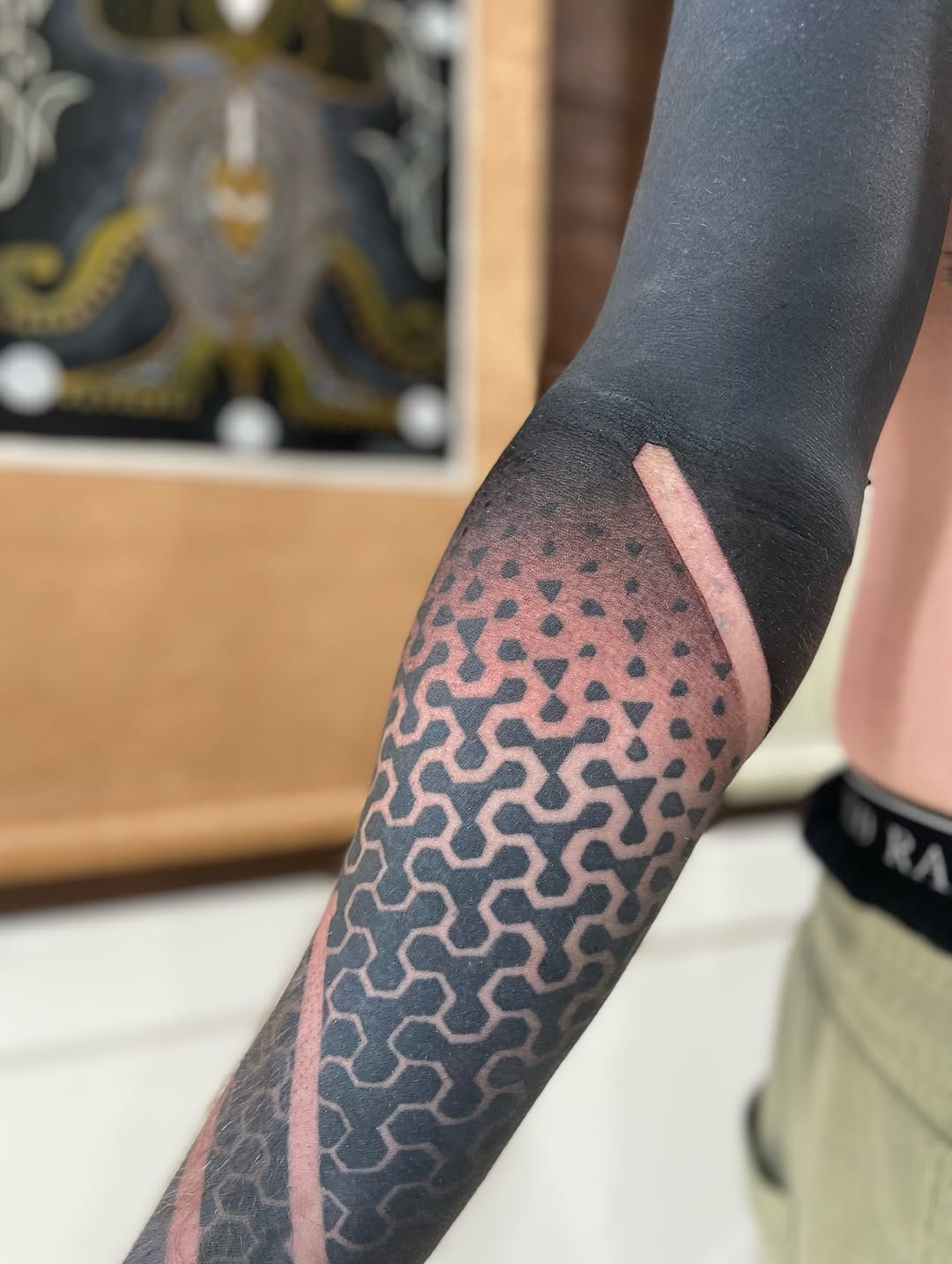 Sleek blackwork forearm sleeve with tessellated chain-link pattern and pink edge accent
