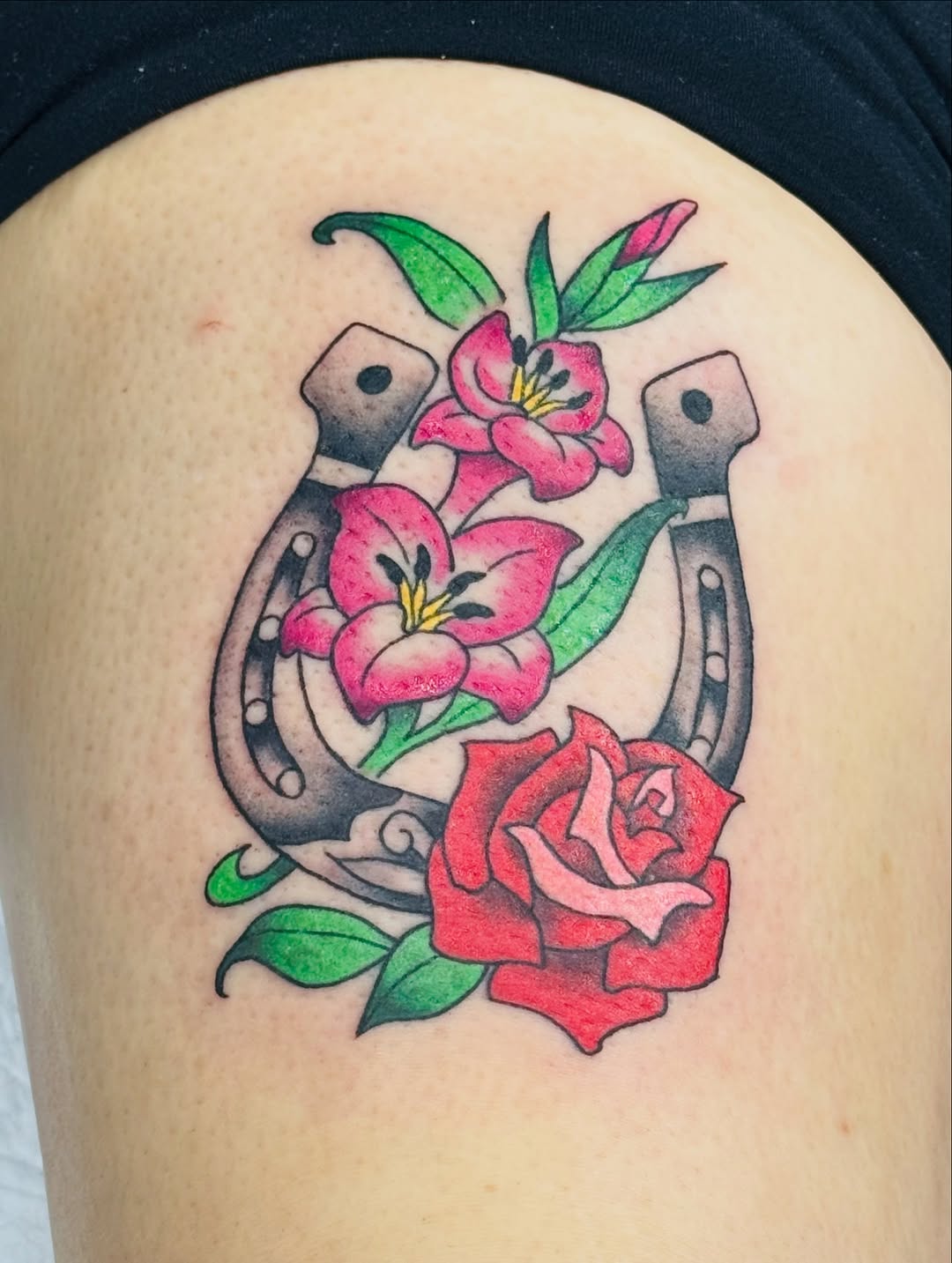Neo-traditional horseshoes cradle bright pink flowers and a rose