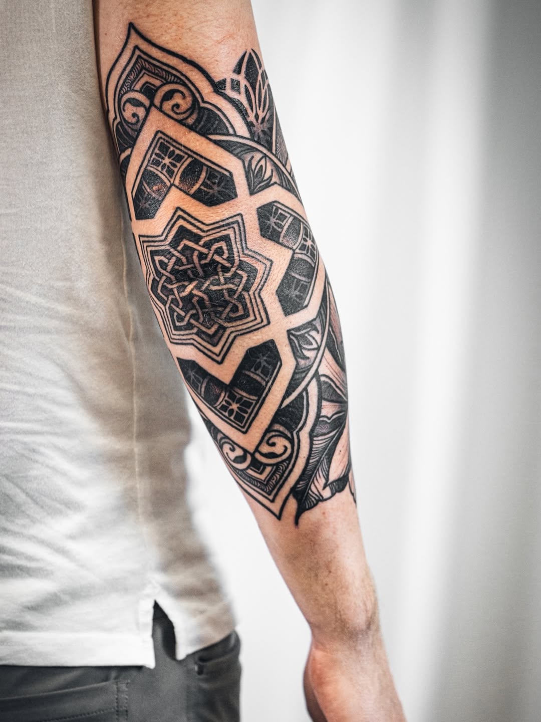 Intricate blackwork forearm tattoo with geometric mandala motifs