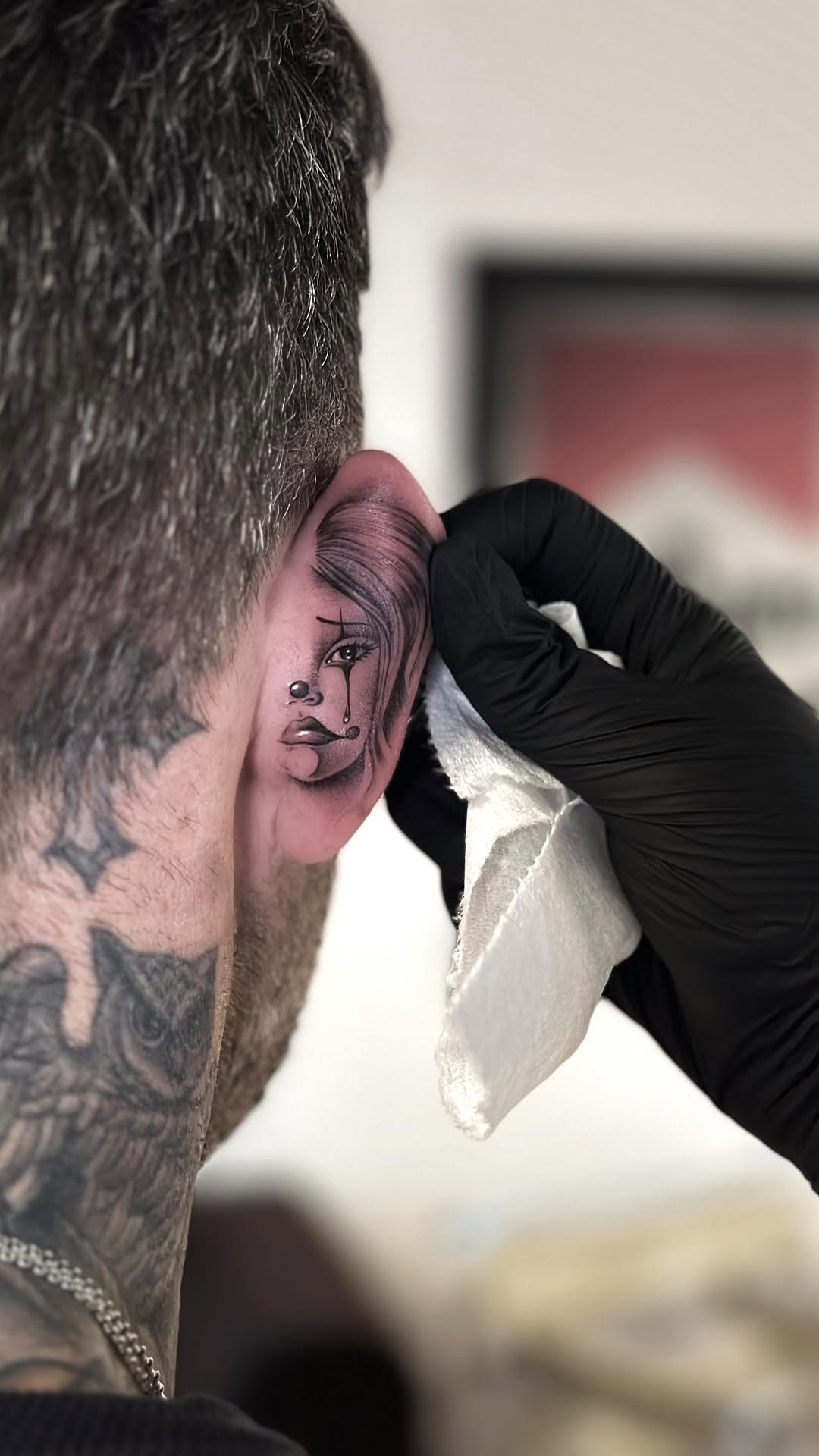 Delicate ear tattoo: haunting shaded portrait with teardrop.