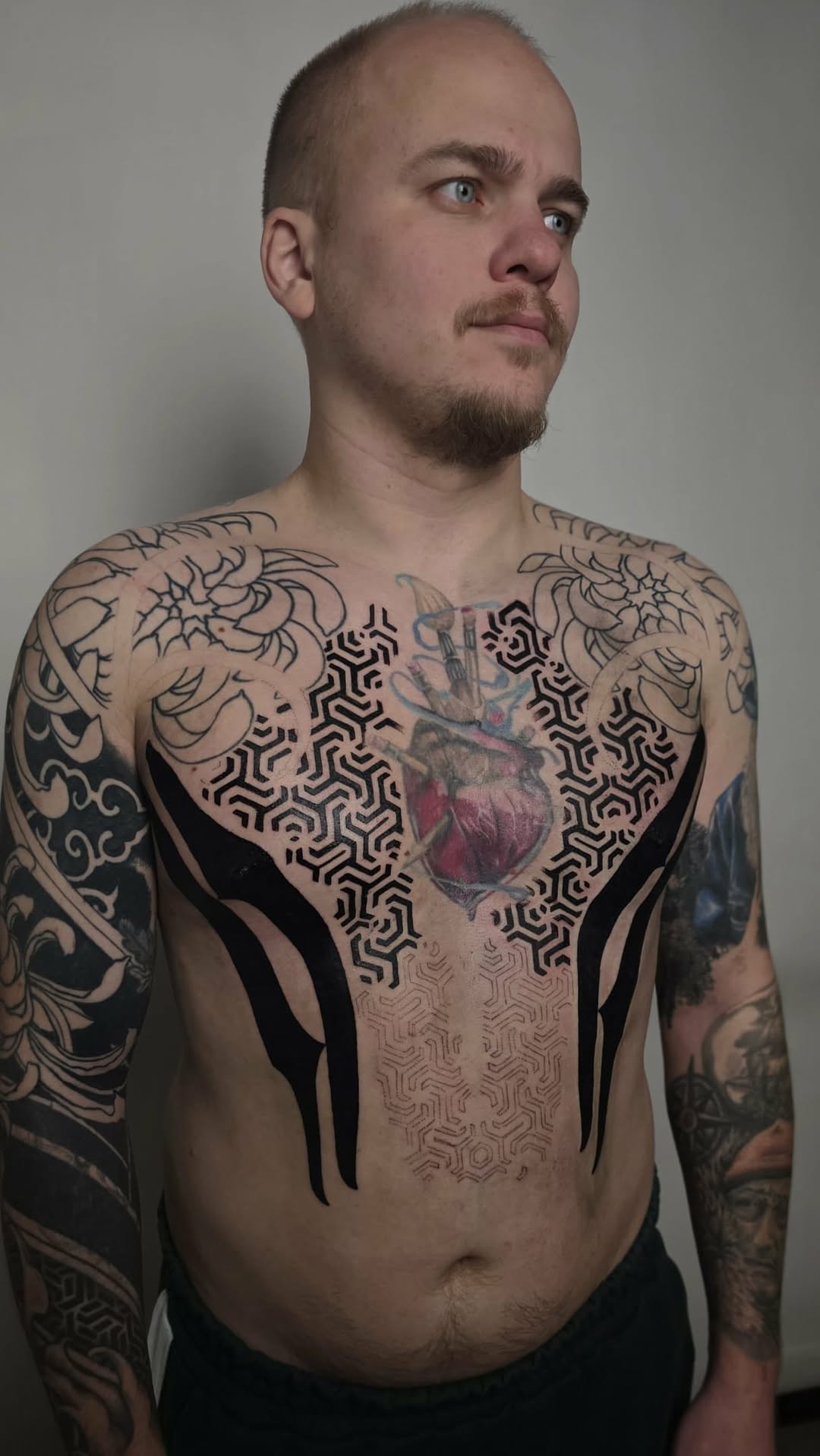 Bold blackwork chest piece with geometric maze patterns and a heart centerpiece.