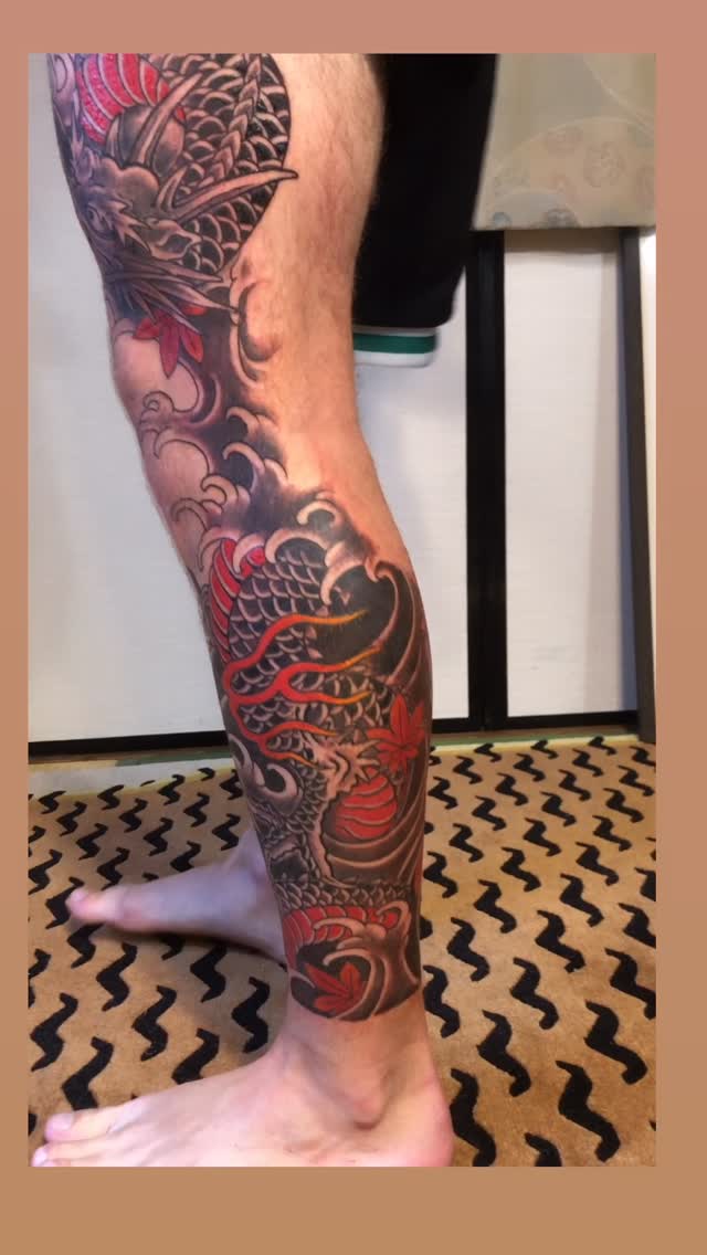Bold Japanese dragon leg sleeve with waves and red accents.