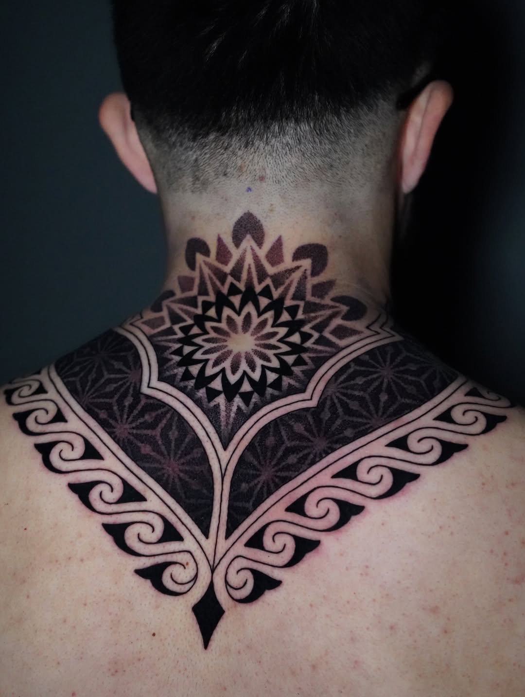 Symmetrical blackwork mandala centerpiece with sweeping curved panels