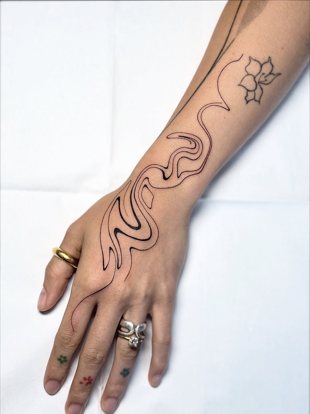 Fluid black-line flow with a small floral accent.