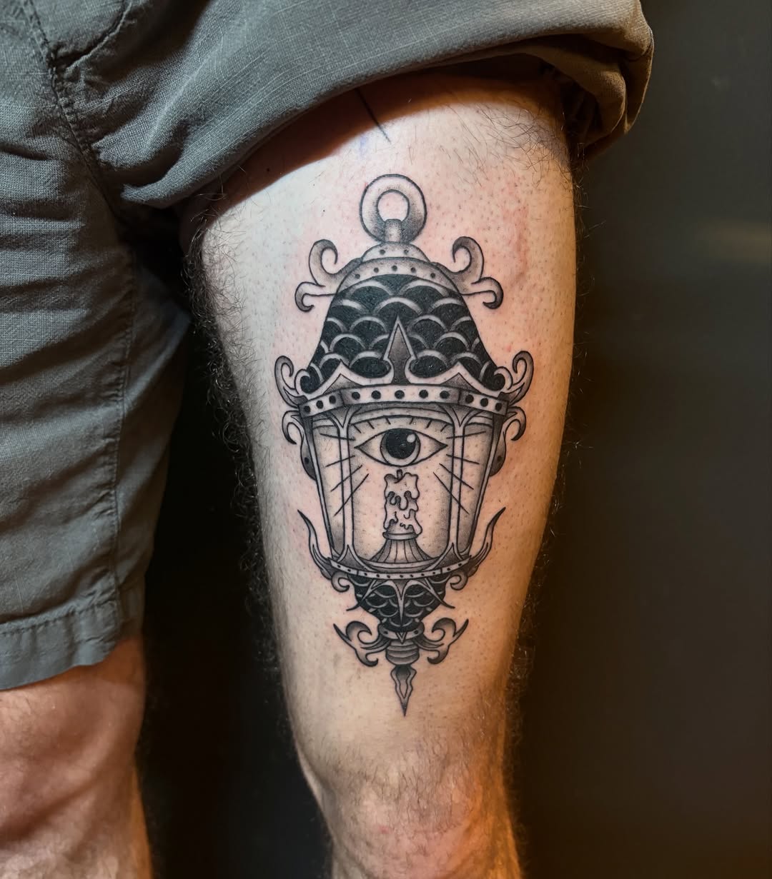 Ornate lantern tattoo with central eye, bold linework.