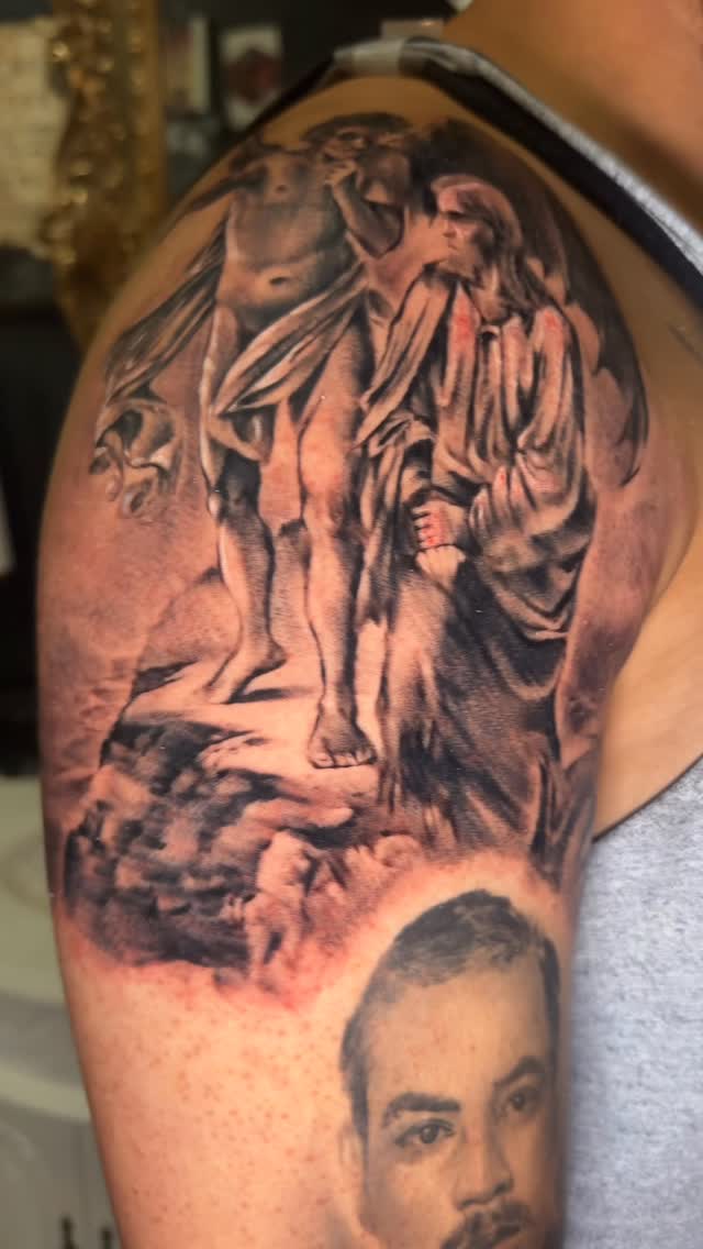 Dramatic black-and-gray tattoo of angelic statue and portrait