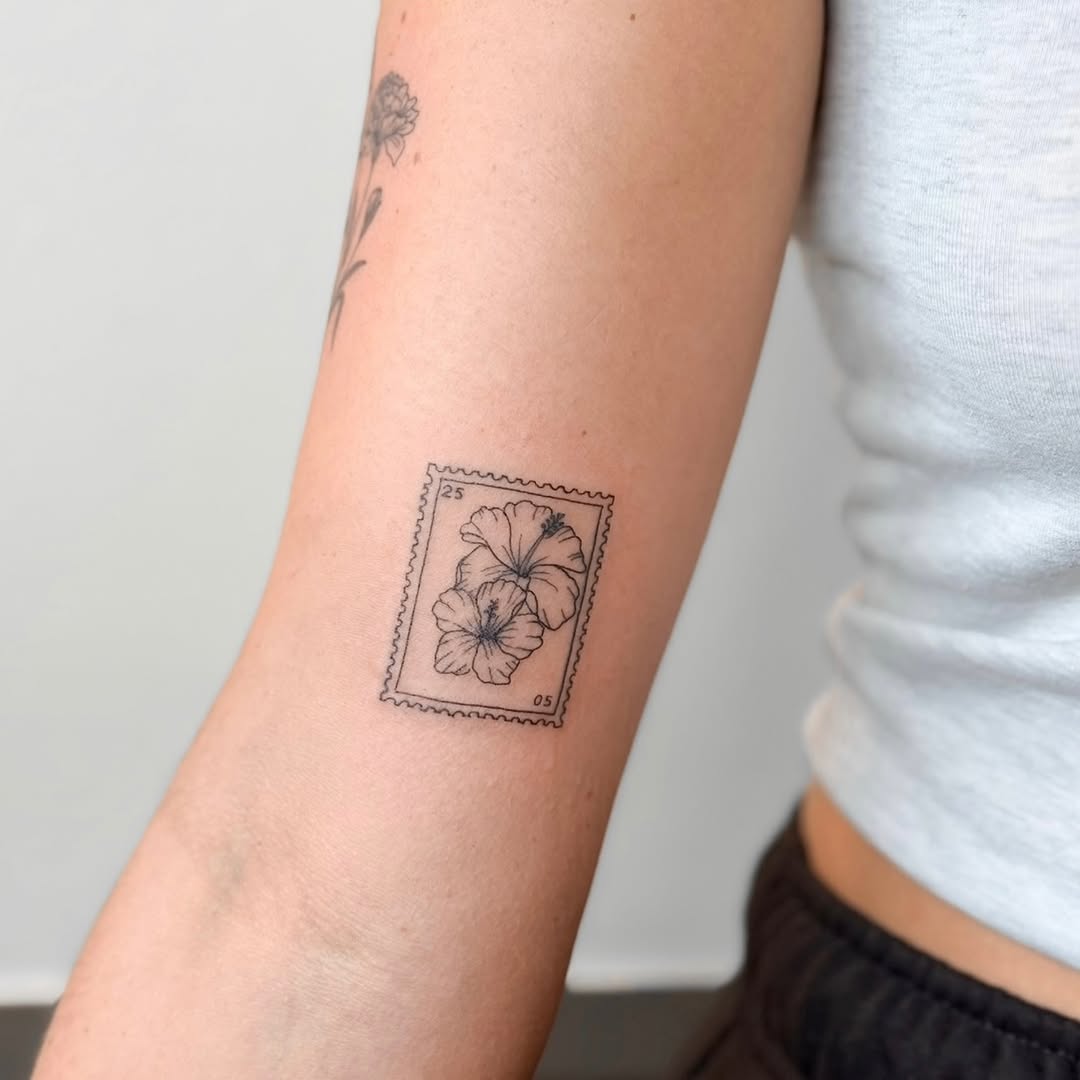 Delicate fine-line hibiscus stamp on the forearm.