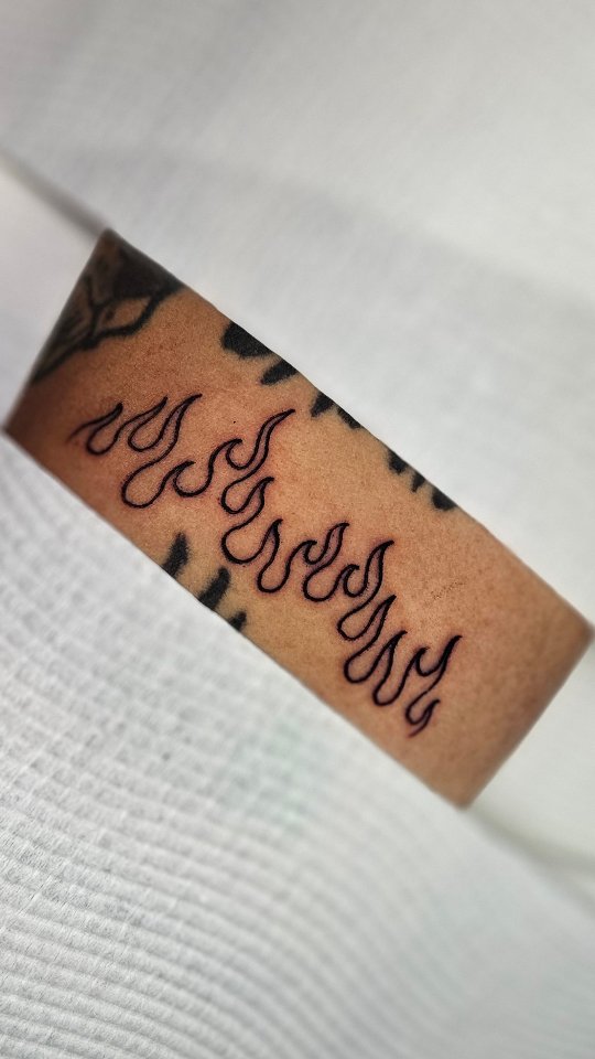 Slim, curling script linework along inner forearm