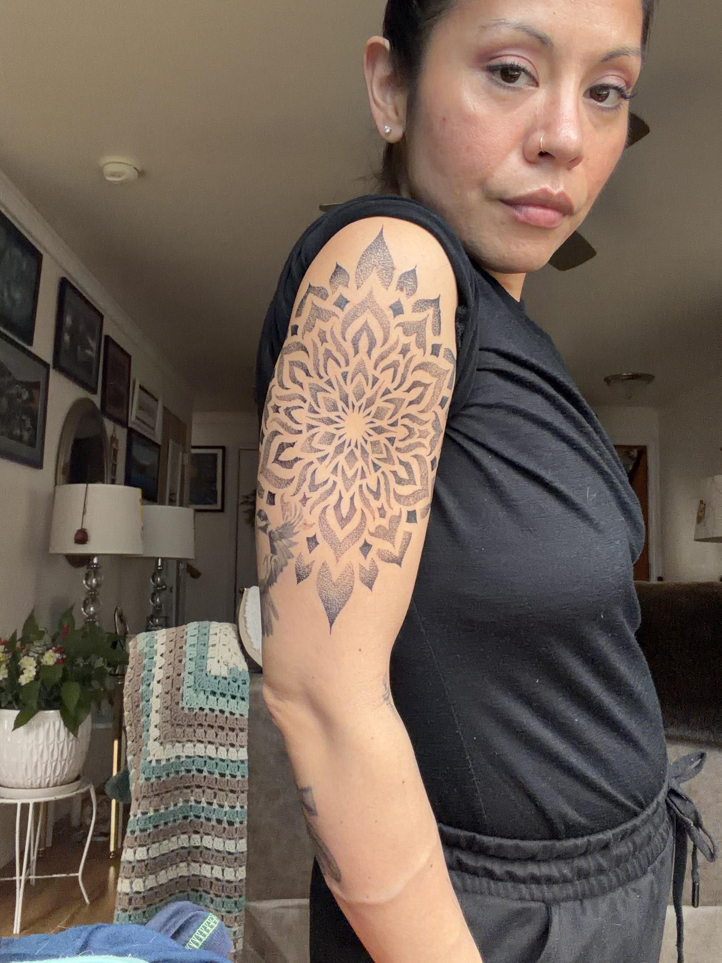 Intricate dotwork mandala on upper arm, bold radial symmetry