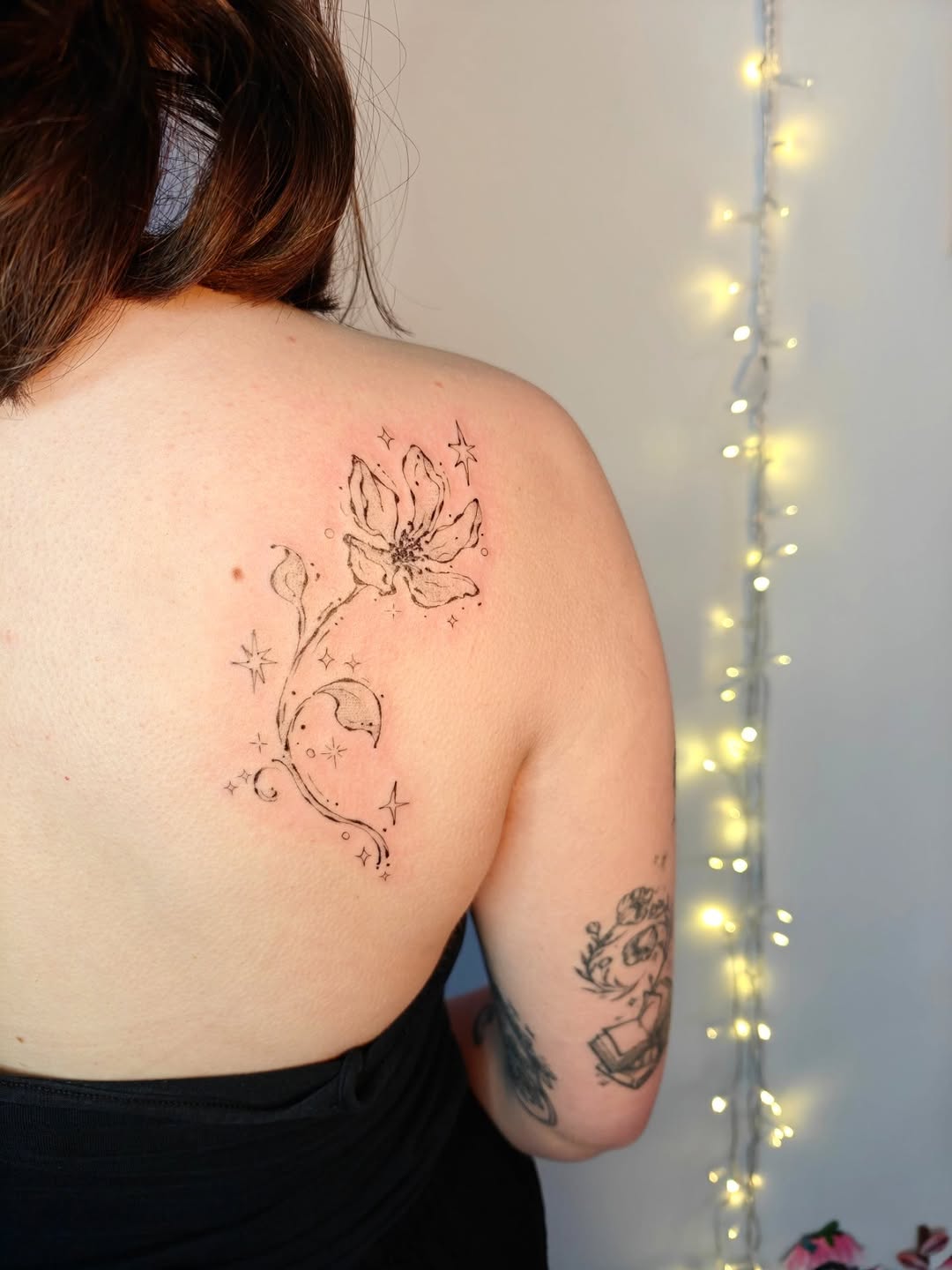 Delicate line-work floral on shoulder blade with stars