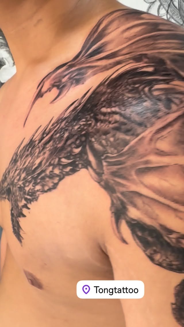 Feathered wing wrap across shoulder with bold blackwork